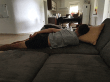 a person laying on a couch with a pillow on their back