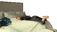 a woman laying on her stomach on a bed with her feet up