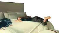 a woman laying on her stomach on a bed with her feet up