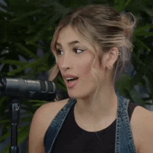 a woman is singing into a microphone and making a funny face .