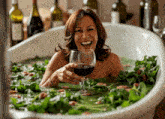 a woman is holding a glass of wine while taking a bath