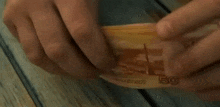 a person is holding a russian ruble bill in their hands .