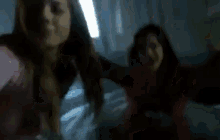 a blurry picture of two women standing next to each other on a bed .