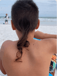 a young boy with a ponytail looks out over the ocean