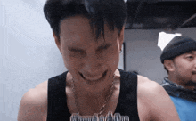 a man wearing a tank top that says ' dumb and dumber ' on it laughs