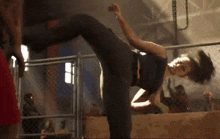 a woman is practicing martial arts in a cage in a gym .