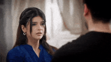 a woman in a blue shirt is looking at a man .