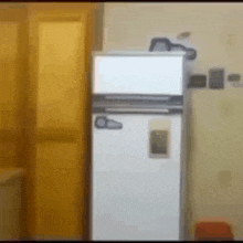a white refrigerator is sitting in a room next to a yellow door