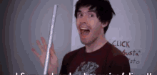 a man holding a stick in front of a white board that says click