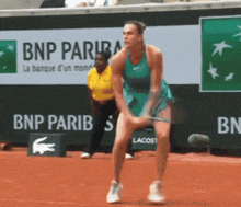 a woman playing tennis in front of an ad for bnp paribas