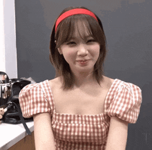 a woman wearing a red headband and a plaid shirt smiles