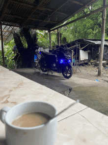 a motorcycle is parked under a roof with a cup of coffee in front of it