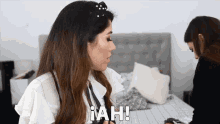 a woman is sitting on a bed with the word iah written on the screen