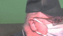 a man wearing glasses and a hat is wearing a mask