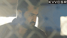 a man with a beard and mustache is behind a fence with a kvvcsr logo above him