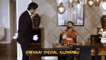 a man in a red shirt is sitting at a table with chennai special kuzhambu written on it