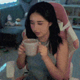 a woman sits in a pink chair holding a cup