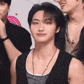 a young man wearing a striped vest and a necklace is standing next to another man .