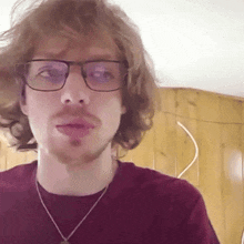 a man with glasses and a beard is wearing a red shirt