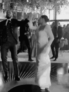 a black and white photo of a bride and groom dancing on a dance floor .