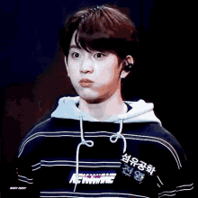 a young man wearing a striped hoodie with the word newwave on it makes a funny face