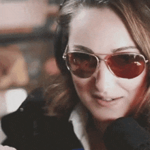 a woman wearing sunglasses and headphones is smiling