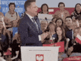 a man stands at a podium in front of a crowd with a sign behind him that says świętokrzyska