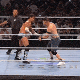 two men are wrestling in a ring with a referee watching