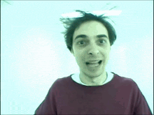 a man in a red shirt is smiling with his mouth wide open