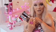 a woman is holding a gun in her hands in front of a pink hello kitty desk .