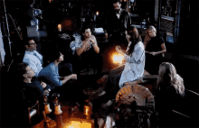 a group of people are gathered around a table with a woman holding a lantern
