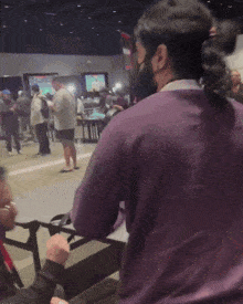 a man in a purple sweater with the word fuck written on his back