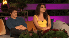 a man and a woman sitting on a couch with flowers in front of them