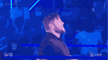 a man stands in a wrestling ring with his arms outstretched in front of a crowd