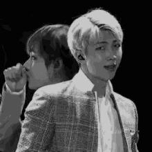 a black and white photo of two young men standing next to each other .