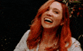a woman with red hair is smiling and laughing