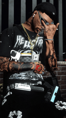 a man wearing a shirt that says hellstar holds a gun