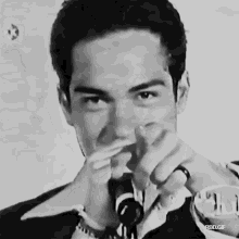 a black and white photo of a man covering his mouth