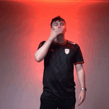 a man covering his mouth with his hand wearing a shirt that says syner
