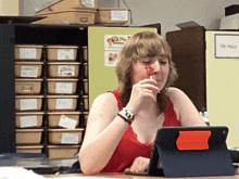a woman sits at a desk with a tablet and a sign that says 7th hour on it