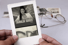 a person holding a picture of a woman named jamilia grier