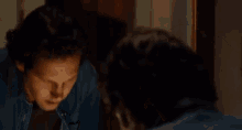 a man is covering his face with his hand while looking at himself in the mirror .