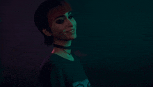 a woman wearing a choker and a black shirt smiles in a dark room