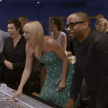 a woman in a green dress is laughing with a man in glasses