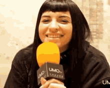 a woman is holding a microphone in her hand and smiling .
