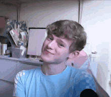 a young man in a blue shirt is smiling and looking at the camera .