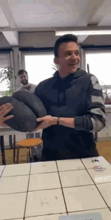 a man in a black hoodie is holding a black pillow