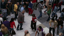 a crowd of people are walking in a hallway and one of them is wearing a red sweater