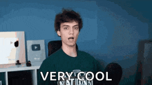 a young man is wearing a green shirt that says `` very cool '' on it .