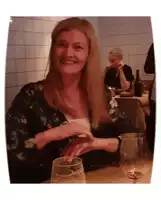 a woman sitting at a table with a glass of wine in front of her
